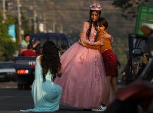 Una joven que celebra sus 15 años posa para una foto en la calle principal de La Campanera, durante la celebración en una iglesia evangélica en Soyapango, El Salvador, el domingo 5 de marzo de 2023. 