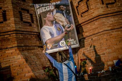 Una joven rinde homenaje al ídolo del fútbol al pasar por un mural colgado en una calle de Barcelona