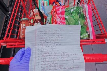 Una lista de supermercado en las manos de un voluntario de Invisible Hands