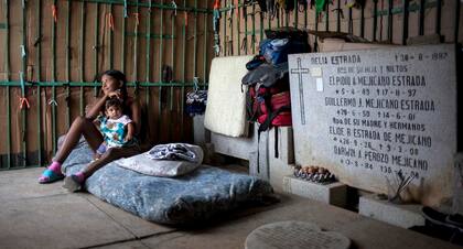 Una madre joven cuida de su hijo en su improvisada casilla en el Cementerio General del Sur