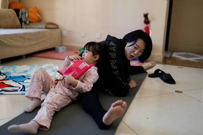 Una madre practica yoga con su hija en su departamento en Pekín