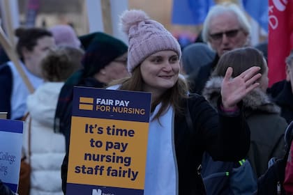 Una manifestante alza un cartel en apoyo al personal de enfermería en huelga por salarios frente al hospital St. Thomas, Londres, martes 20 de diciembre de 2022. El cartel dice, "es hora de pagar al personal de enfermería un salario justo". (AP Foto/Alastair Grant)