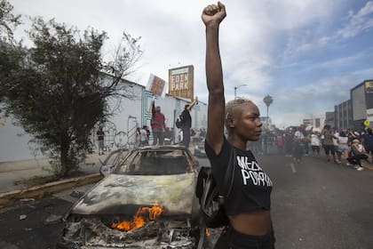 Una manifestante frente a un auto de policía en llamas en Los Ángeles, el 30 del mes pasado