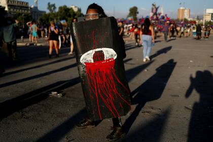 Una manifestante muestra un cartel con un ojo sangriento, como alusión a las heridas oculares que sufrieron miles de personas durante las protestas en Chile