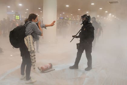 Una manifestante protege su cara del humo frente a un policía dentro del aeropuerto de El Prat en Barcelona el 14 de octubre de 2019