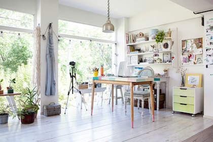Una mesa de fórmica con tapa en découpage hace de escritorio, con una silla estilo Luis XV y una antigua cajonera de placard tuneada con un tratamiento de pintura degradé y ruedas cromadas