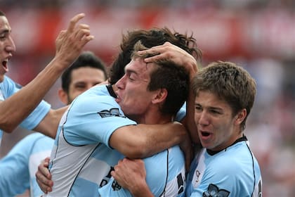 Con la camiseta de Racing, recibe los abrazos de sus compañeros (entre ellos, un juvenil Vietto) tras un gol a River en el Monumental, en 2012