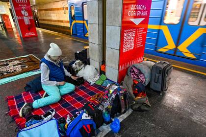 Una mujer acaricia a su perro en una estación de metro subterránea utilizada como refugio antibombas en Kiev 