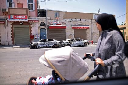 Una mujer árabe israelí observa autos quemados en la ciudad central israelí de Lod