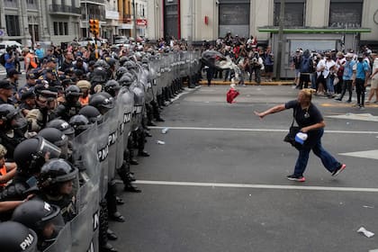 Una mujer arroja una bolsa de basura a la policía que bloquea una manifestación contra la escasez de alimentos en los comedores populares y las reformas económicas propuestas por el presidente Javier Milei