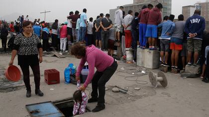 Una mujer ayuda a una niña a bajar desde la terraza de un edificio desde donde los aficionados ven el campeonato de fútbol callejero el Porvenir en Lima, Perú