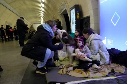 Una mujer besa a su perro mientras otras personas se reúnen en el metro de Kiev, usándolo como refugio antibombas en Kiev, Ucrania