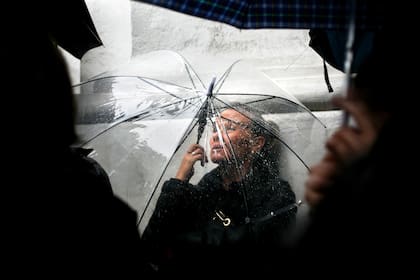 Una mujer busca reparo de la lluvia durante una marcha del colectivo #NiUnaMenos, el 19 de octubre de 2016, en Buenos Aires