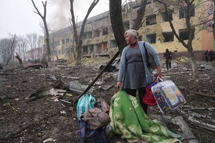 Una mujer camina afuera de un hospital de maternidad que resultó dañado por los bombardeos en Mariupol
