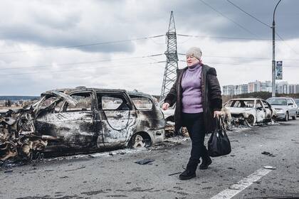 Una mujer camina cerca de automóviles quemados en el puente de Irpin el 7 de marzo de 2022.