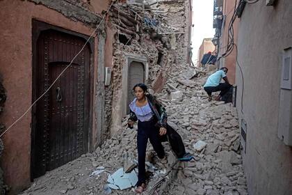 Una mujer camina con sus pertenencias entre los escombros en la antigua ciudad de Marrakech dañada por el terremoto el 9 de septiembre de 2023