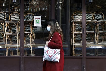 Una mujer camina frente a un restaurante cerrado, hoy, en París