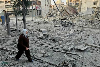 Una mujer camina junto a edificios destruidos en el lugar de un ataque aéreo israelí nocturno que tuvo como objetivo los suburbios del sur de Beirut, en el barrio de Hadath