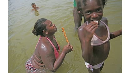 Una mujer come gambas, mientras que se sientan en el agua en el estanque artificial conocido como piscinao, o piscina grande al norte de Río de Janeiro, en Brasil