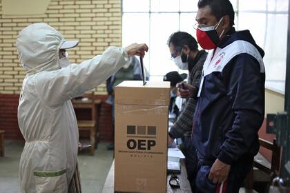 Una mujer con equipo de protección como medida preventiva contra la propagación del nuevo coronavirus, emite su voto en un colegio electoral en La Paz el 18 de octubre de 2020 durante las elecciones generales de Bolivia