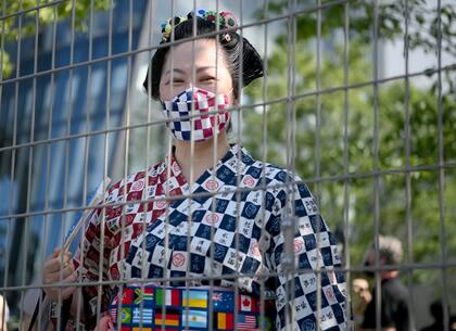 Una mujer con ropa tradicional mira desde detrás de una valla antes de la ceremonia de apertura de los Juegos Olímpicos de Tokio 2020 en el Estadio Olímpico el 23 de julio de 2021 en Tokio, Japón.