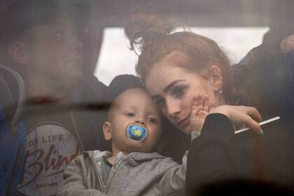 Una mujer, con su hijo en brazos, sentada en un bus antes de abandonar Kiev, Ucrania, el 24 de febrero de 2022. (AP Foto/Emilio Morenatti)