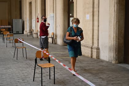 Una mujer con una mascarilla se va después de emitir su voto en un colegio electoral en el centro de Roma el 20 de septiembre de 2020