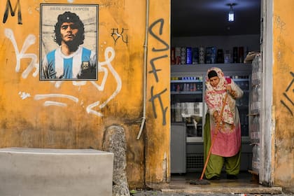 Una mujer de pie junto a un mural dedicado a Diego Armando Maradona, del artista callejero Harry Greb, distrito de Trastevere de Roma
