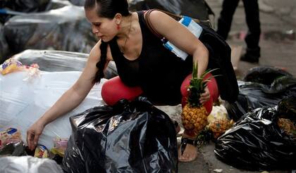 Una mujer embarazada recolecta frutas tiradas por un supermercado
