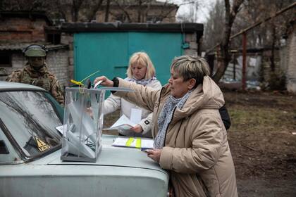Una mujer emite su voto en un colegio electoral móvil durante la votación anticipada de las elecciones presidenciales de Rusia en Donetsk, Ucrania controlada por Rusia, en medio del conflicto Rusia-Ucrania el 14 de marzo de 2024. (STRINGER / AFP)