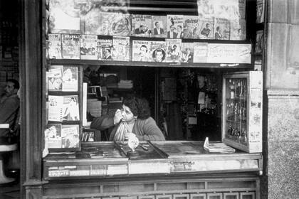 Una mujer en un puesto de venta de libros, revistas y artículos de tocador en el microcentro.
