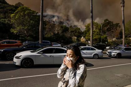 Una mujer habla por teléfono mientras evacúa un barrio amenazado por el incendio forestal de Palisades