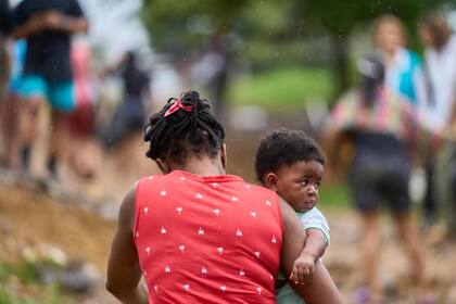 Una mujer haitiana sujeta a su hijo mientras llega en una pequeña embarcación al Centro de Acogida Temporal de Migrantes de Lajas Blancas, luego de cruzar la selva del Darién