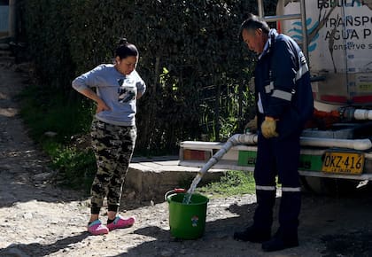 Una mujer junta agua potable de un camión cisterna en La Calera, cerca de Bogotá, el 10 de abril de 2024. 