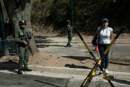 Una mujer junto a dos soldados mientras otros miembros de la oposición entregan copias de una ley de amnistía cerca de Ft. La base militar de Tiuna en Caracas