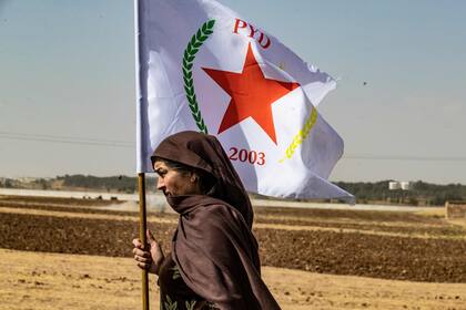 Una mujer kurda siria ondea la bandera del Partido de la Unión Democrática (PYD) durante una manifestación contra las amenazas turcas en la ciudad de Ras al-Ain, en la provincia siria de Hasakeh, cerca de la frontera turca