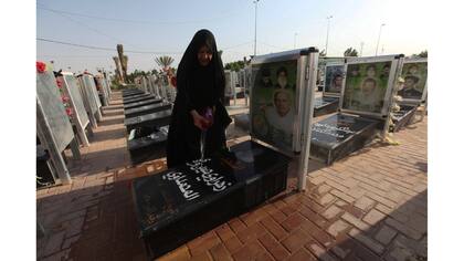 Una mujer lava la tumba de un pariente