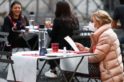 Una mujer lee un menú mientras se sienta en la terraza de un restaurante en el centro de Roma, el 25 de octubre de 2020, mientras el país enfrenta una segunda ola de infecciones por Covid-19