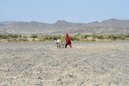 Una mujer lleva latas de agua en una carretilla en la zona de Koh-e-Sabz, en la provincia de Baluchistán, al suroeste de Pakistán, donde Irán lanzó un ataque aéreo, el 18 de enero de 2024. (Banaras KHAN / AFP)�