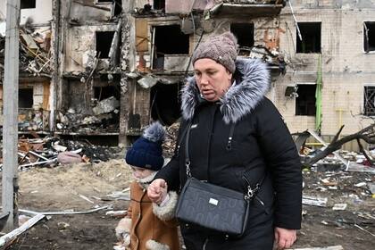 Una mujer lleva un niño a través de la calle Koshytsa, en los suburbios de Kiev