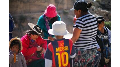 Una mujer lleva un sombrero tipico y un nino la camiseta del numero 10 del Barcelona, Lionel Messi
