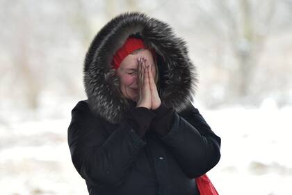 Una mujer llora cuando sus familiares cruzan un puente destruido mientras evacuan la ciudad de Irpin, al noroeste de Kiev