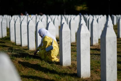 Una mujer llora junto a la tumba de un familiar, víctima del genocidio de Srebrenica, en el Cementerio y Monumento de Potocari, Bosnia, el viernes 11 de julio de 2025. (AP Foto/Darko Bandic)