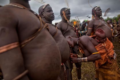 Una mujer mide el abdomen de su marido, que es parte de la ceremonia para premiar al hombre más obeso de la aldea