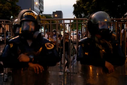 Una mujer mira desde una barrera policial que bloquea una calle que conduce al Congreso en Lima, Perú, el martes 31 de enero de 2023. 