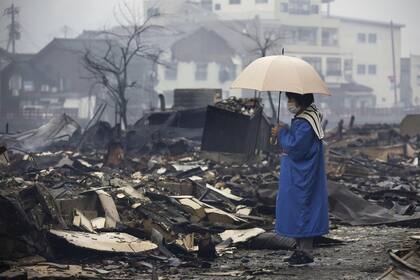 Una mujer mira el mercado quemado por un incendio tras los terremotos en Wajima.