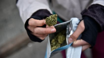 Una mujer muestra un paquete de marihuana comprado en una farmacia en Uruguay