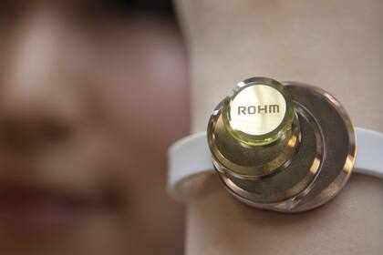 Una mujer muestra una pulsera desarrollada por Rohm, que tiene la particularidad de medir el pulso y enviar los datos a un teléfono celular para un análisis preliminar del estado de salud del portador