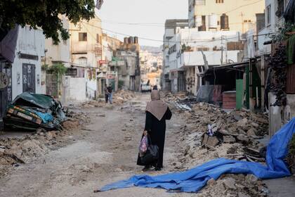 Una mujer palestina camina por una calle dañada en el campo de refugiados de Jenin, en Cisjordania, el 5 de julio de 2023, después de que Israel retirase sus fuerzas del bastión miliciano, lo que puso fin a una intensa operación de dos días que mató a por lo menos 13 palestinos, expulsó a miles de personas de sus casas y dejó un rastro de destrucción a su paso. (AP Foto/Majdi Mohammed)