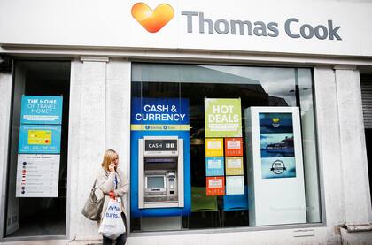 Una mujer parada enfrente a una tienda de Thomas Cook